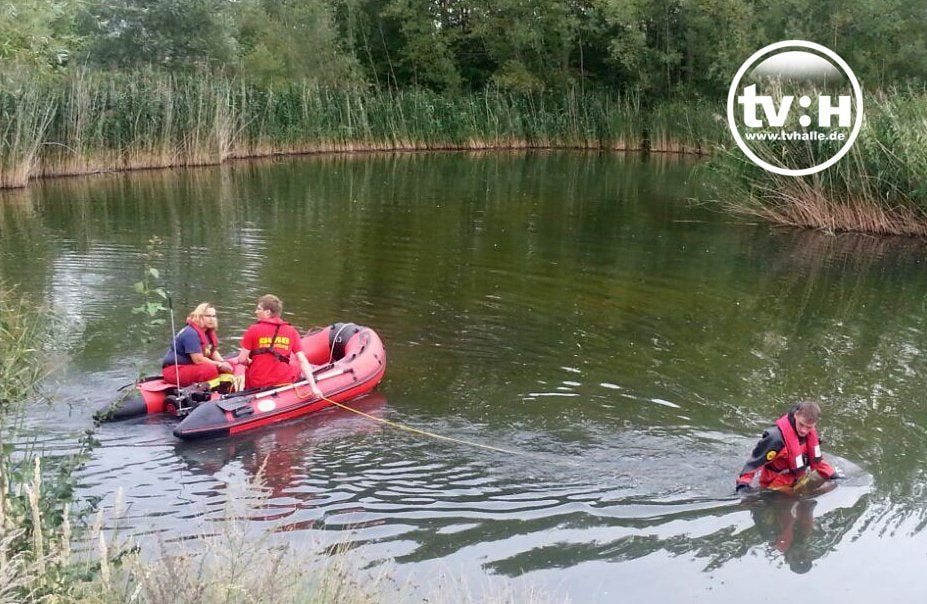 Einsatzkräfte der DLRG suchen einen Teich in Halle-Neustadt ab.