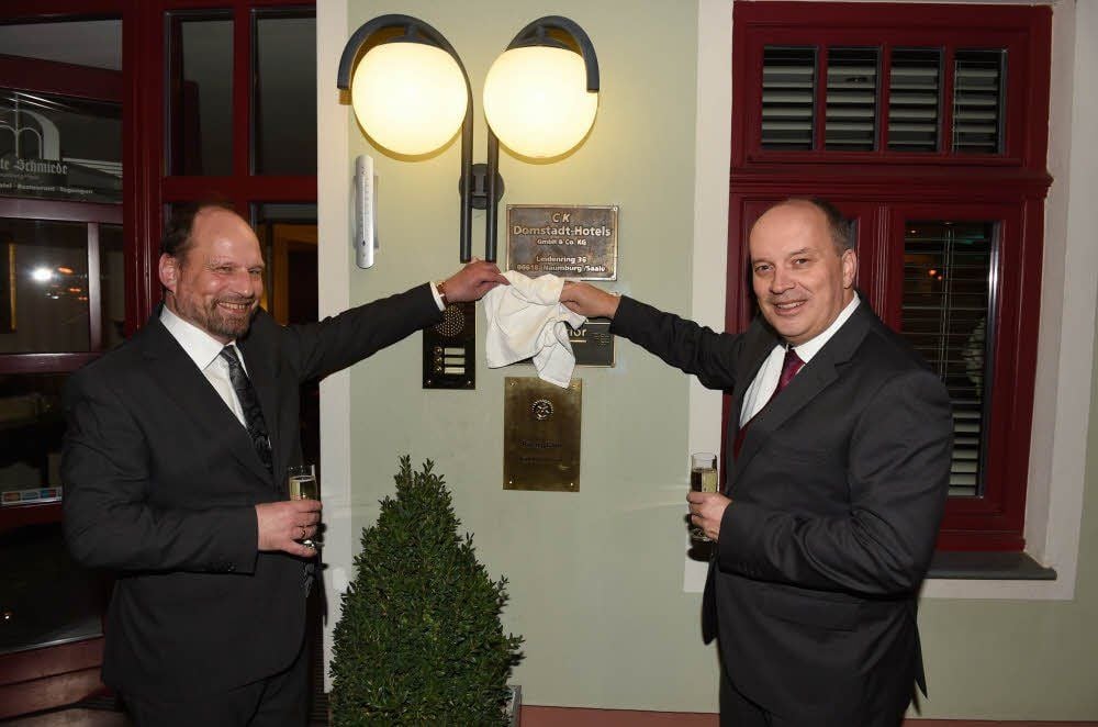 Am Restaurant „Zur Alten Schmiede“ bringen Präsident Udo Burkhardt (r.) und Dirk Stötter die Tafel für den neuen Tagungsort an.