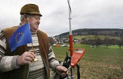 Mit einem EU-Fähnchen in der Hand steht ein Landwirt am Mittwoch (03.01.2007) bei Hasselroth Meerholz auf einem Berg an einem Gerät, das die Koordinaten für den europäischen Mittelpunkt anzeigt. (Foto: dpa)