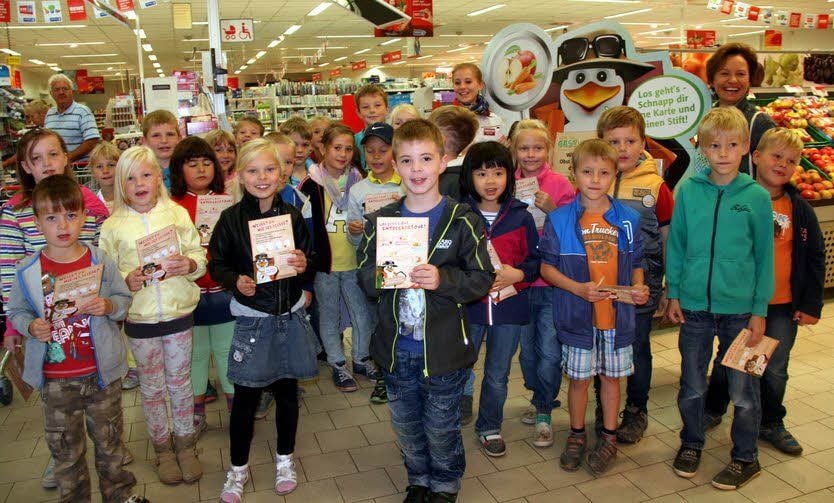 Mit „Pinguin Paul“, der künftigen Lehramtsstudentin Jana Kühnast und Klassenleiterin Marion Kneist lernen die Schüler der Klasse 2c bei einer Unterrichtsstunde im Rewe-Markt jede Menge über gesunde Ernährung.