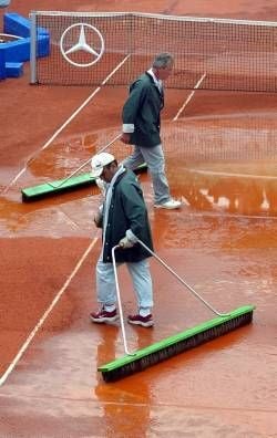 Zwei Arbeiter versuchen am Dienstag (16.07.2002) beim Stuttgarter ATP Weissenhof Tennis-Turnier auf dem Centre Court mit Besen den Platz trocken zu legen. Durch den Regen am Dienstag wurde der Spielplan durcheinander gebracht.