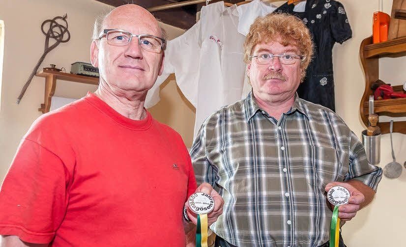 Hans-Dieter im Würzberger, Vorsitzender des Kultur- und Heimatvereins Ragösen (li.) und Ortsbürgermeister Hans-Peter Klausnitzer präsentieren die Festplaketten.