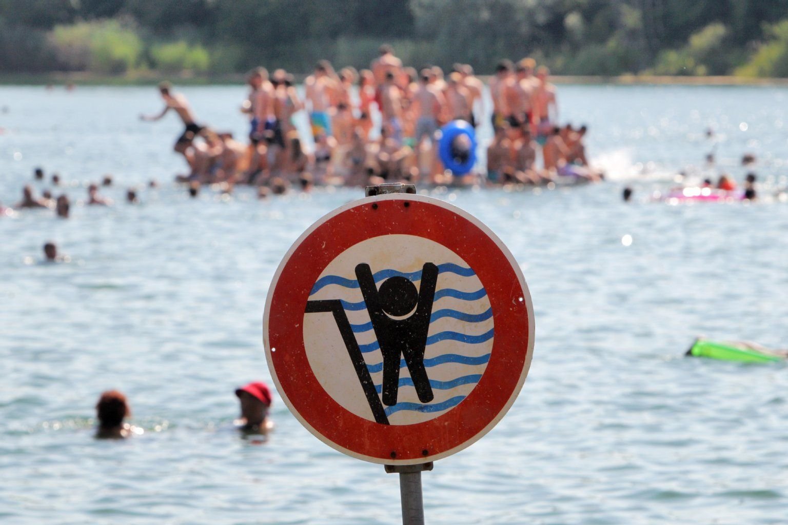 Ein Schild warnt in einem Badesee in Hessen Schwimmerinnen und Schwimmer vor einem stark abfallenden Ufer.