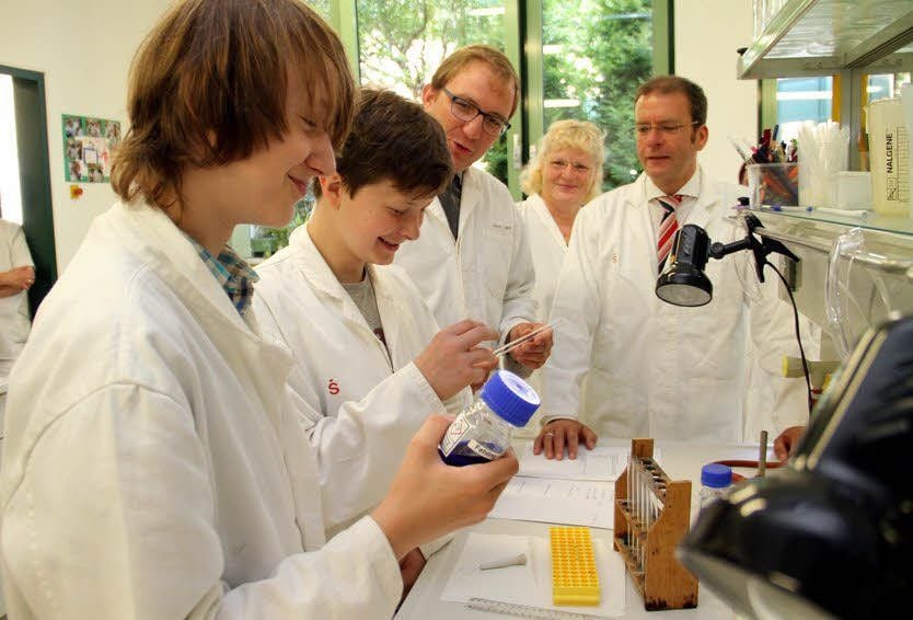 Landrat Markus Bauer und Stiftungschef Hans Michael Strube schauen Schülern aus Egeln beim Experimentieren über die Schultern. Zuvor hatten beide einen Scheck von insgesamt 15 000 Euro überreicht.