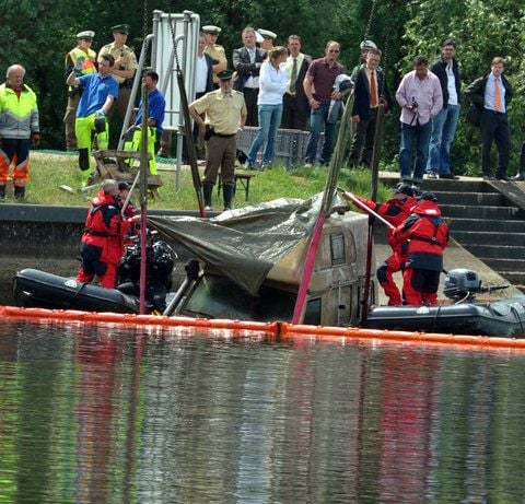 Aus der Donau wird bei Bertoldsheim (Oberbayern) ein Auto geborgen und von Polizisten mit einer Plane abgedeckt. (FOTO: DPA)
