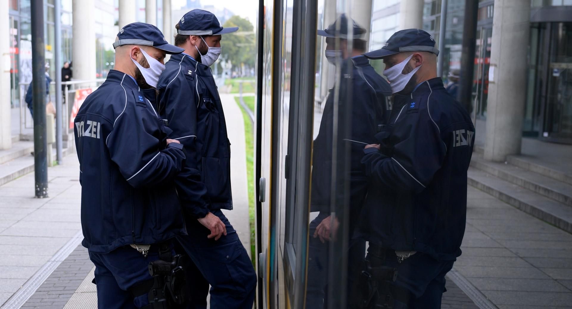 Zwei Polizisten besteigen eine Straßenbahn, um die Einhaltung der Maskenpflicht zu kontrollieren.
