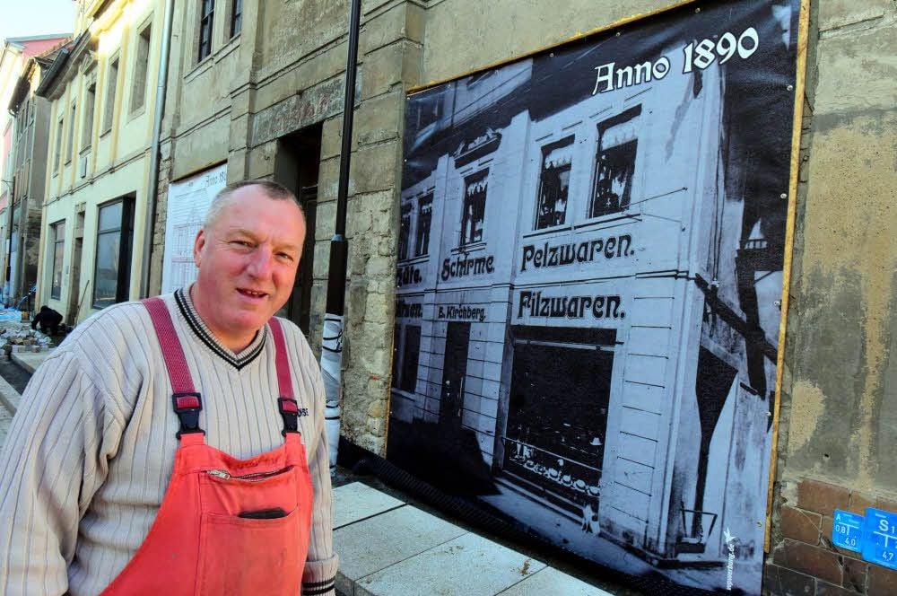 André von Grzymala vor dem Haus, das von alten Bildern geschmückt wird.