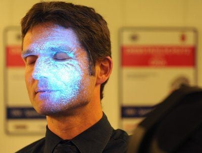 Der Leiter der Polizei-Inspektion 5 für Wirtschaftskriminalität, Lars van Beek, macht in Bremen mit einer UV-Lichtlampe, die durch künstliche DNA hinterlassenen Spuren auf seinem Gesicht deutlich. (FOTO: DPA)