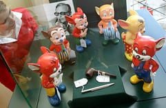 Eine Frau betrachtet im Auktionshaus Sotheby's in München (Oberbayern) von Prominenten bemalte «Fix & Foxi»-Figuren. Im Hintergrund ist ein Bild von Rolf Kauka zu sehen, aus dessen Sammlung die Figuren stammen. (Foto: dpa)