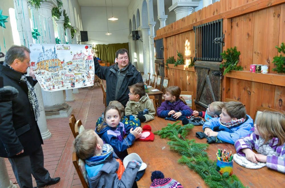 Michael Schuster (links) und Steffen Fischer stellen Kindern aus der Kita „Angelika Hartmann" im Marstall das Wimmelbuch vor.