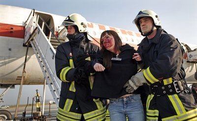 Zwei Feuerwehrmänner retten eine junge Frau während einer Katastrophenübung auf dem Flughafen Halle-Leipzig. (Foto: dpa)