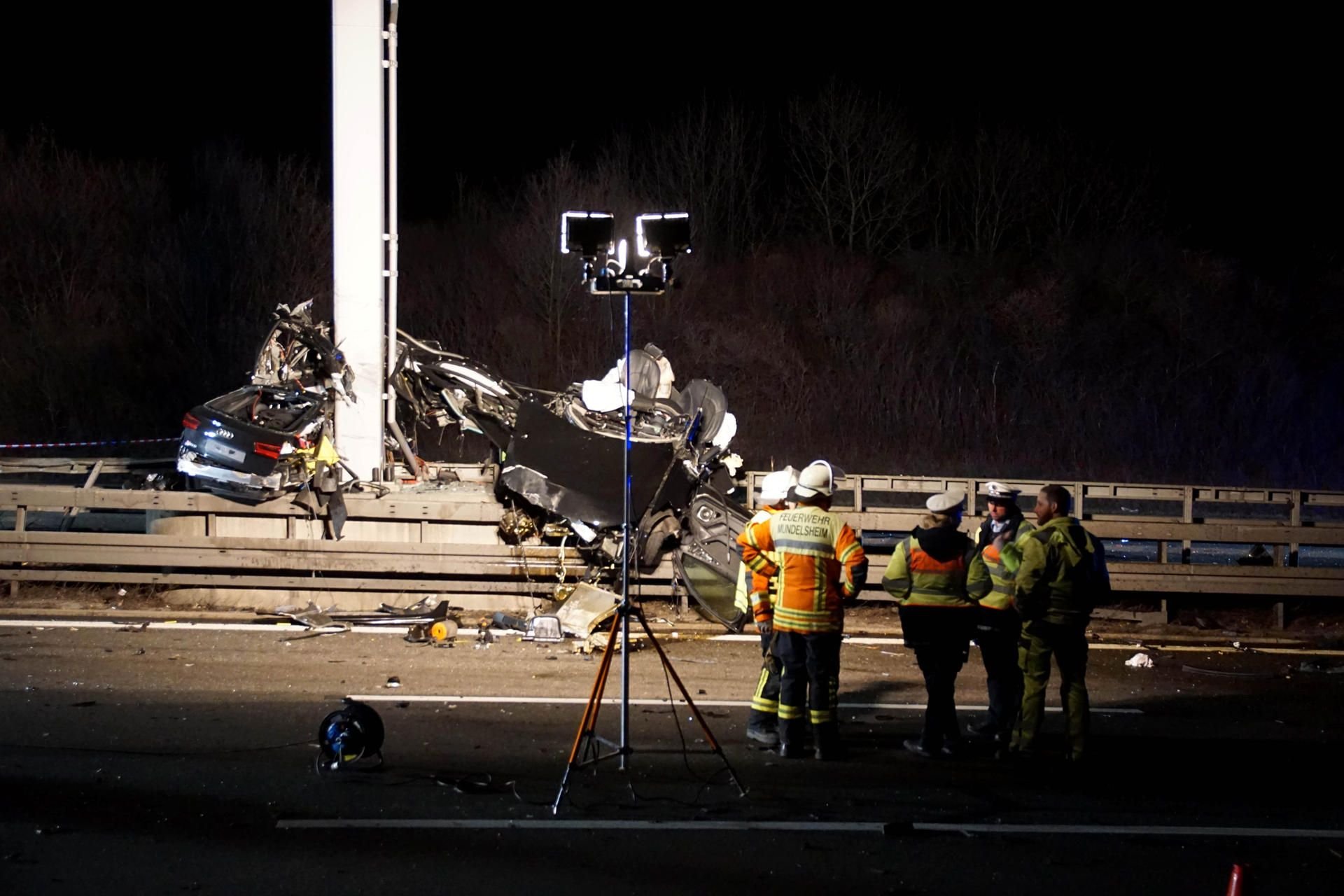 Einsatzkräfte der Feuerwehr und Polizei stehen neben dem Autowrack auf de Autobahn 81.
