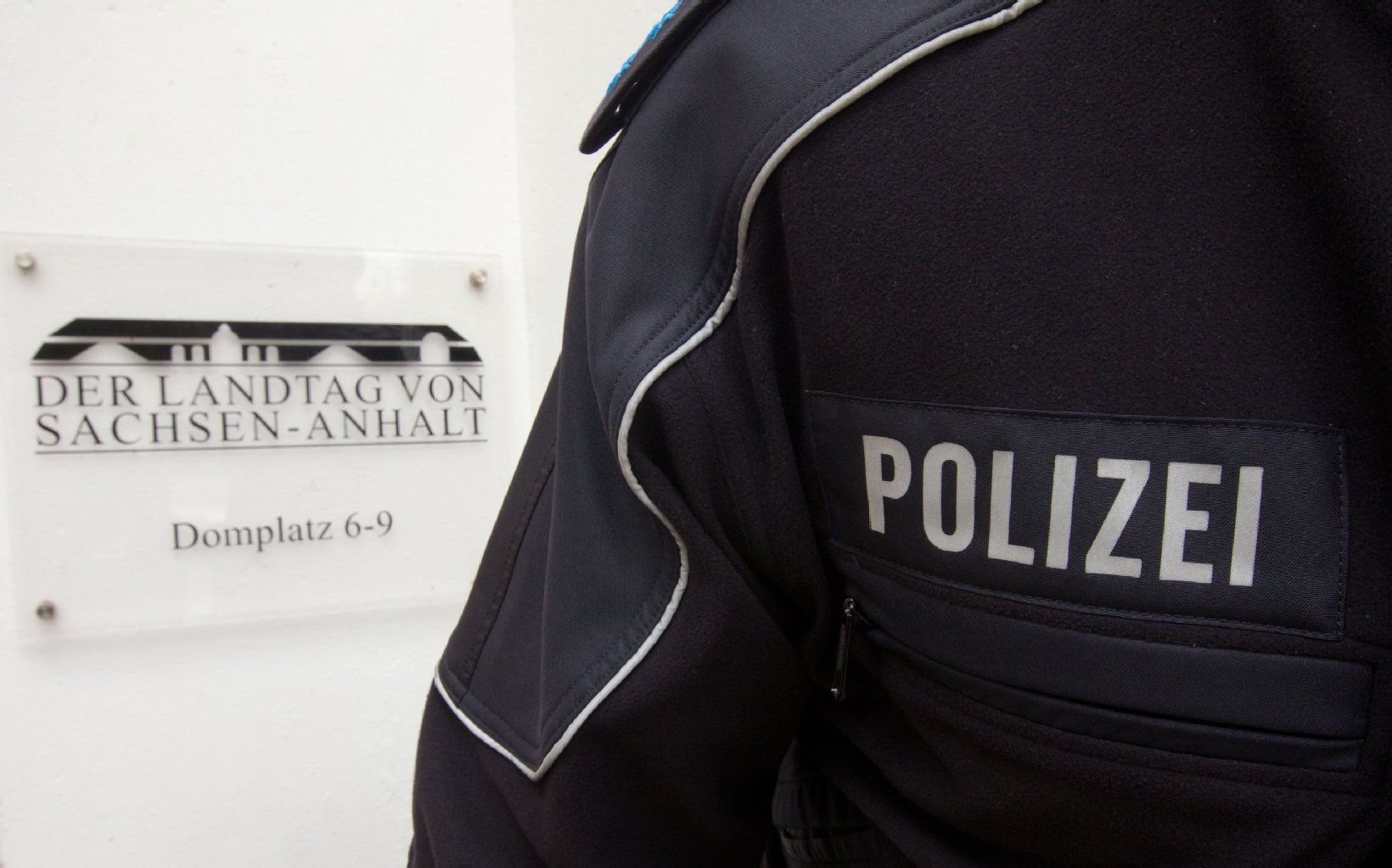 Ein Polizist in Uniform steht vor dem Schild des Landtages von Sachsen-Anhalt in Magdeburg.