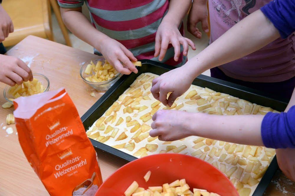 Der Kuchenteig wird mit Apfelstückchen belegt.