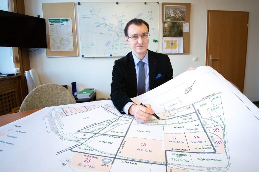 Arvid Friebe sitzt in seinem Büro vor einer großen Karte des Chemie- und Industrieparks Zeitz, der auf Investitionen hofft.