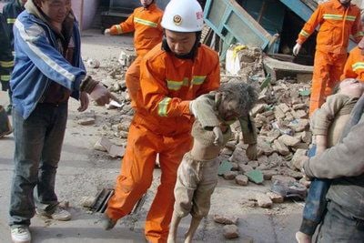 Feuerwehrleute tragen ein Kind aus den Trümmern eines eingestürzten Gebäudes. Ein Erdbeben der Stärke 7,1 Erdbeben hat Chinas Nordwesten schwere Verwüstungen angerichtet. (FOTO: DPA)