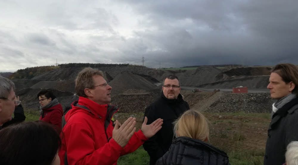 Klaus Kindeleit (rote Jacke) von der Bürgerinitiative erklärt dem Landtagsabgeordneten Gebhardt (r.) an der Halde, welche Gefahren er sieht.
