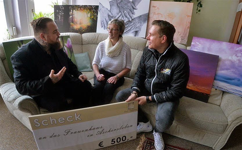 Christian Wolf (links) übergibt zusammen mit Torsten Schubert von Fine Art Print.de den Scheck an Monika Pech (Mitte) vom Frauenhaus.