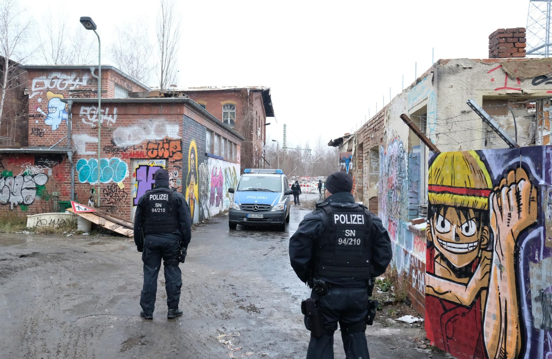 Polizisten stehen vor einem ehemaligen Umspannwerk der Bahn.