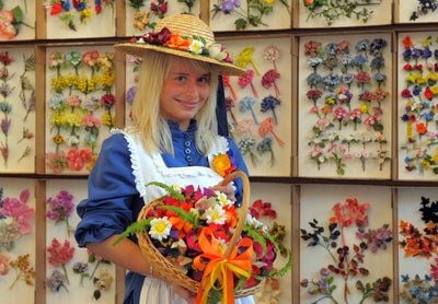 Adrienne Lantos, das «Sebnitzer Blumenmädchen», steht in der Stadthalle Sebnitz vor einer Wand mit Musterkartons voller Kunstblumen. (FOTO: DPA)