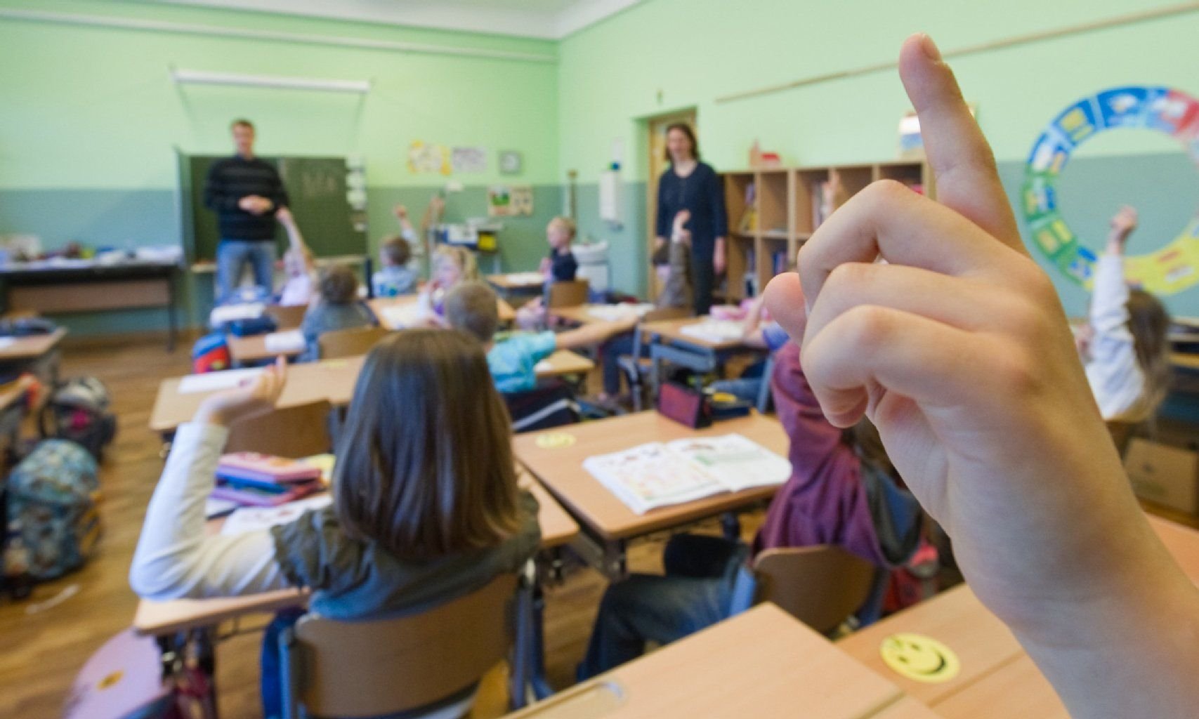 In einer ersten Klasse in einer Grundschule melden sich Kinder während des Unterrichts.