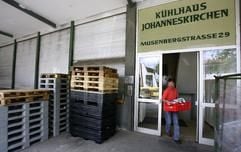 Ein Polizeibeamter trägt nach einer Razzia bei einem Fleisch-Großhändler in München eine Kiste mit Aktenordnern aus den Büros der Firma. (Foto: dpa)