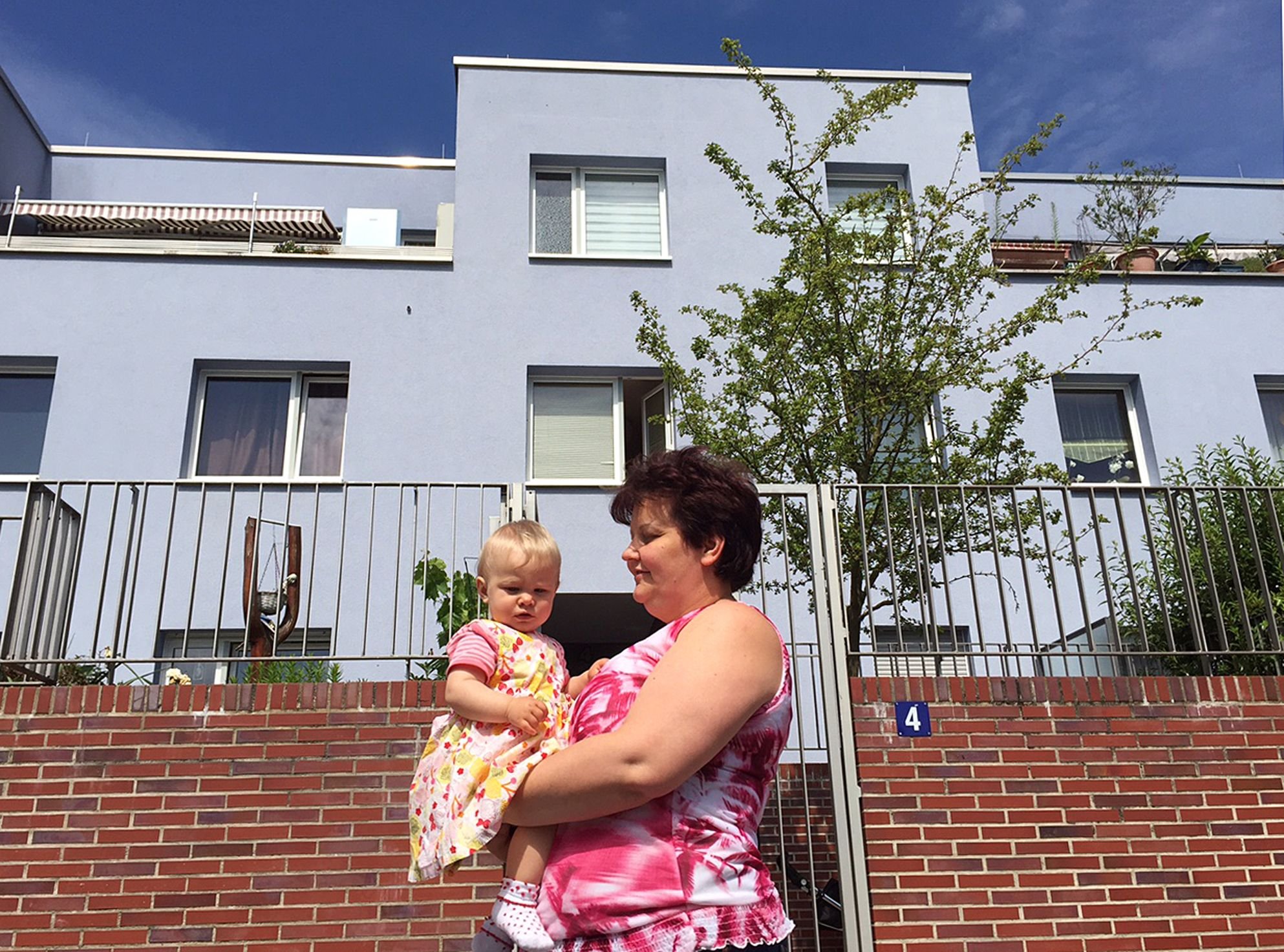 Die Anwohnerin Olga Müller und die kleine Evelin stehen in Leinefelde-Worbis vor einem umgebauten Wohnblock.