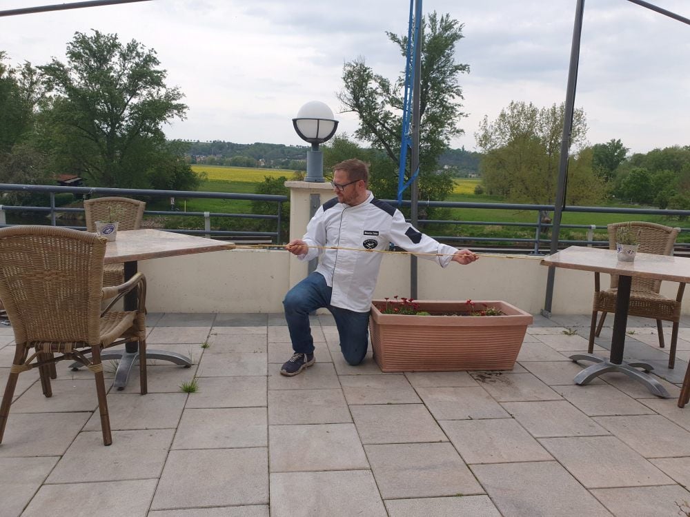 Maurice Tober misst den Sicherheitsabstand zwischen den Tischen auf der Terrasse seiner Gaststätte „Bootshaus Weißenfels“.