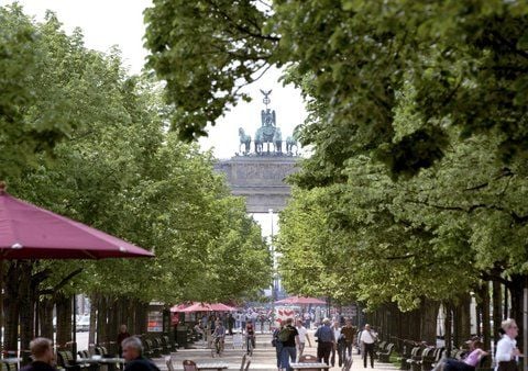 Spaziergänger laufen unter den Schatten spendenden Bäumen auf der Straße Unter den Linden in Berlin zum Brandenburger Tor. (ARCHIVFOTO: DPA)