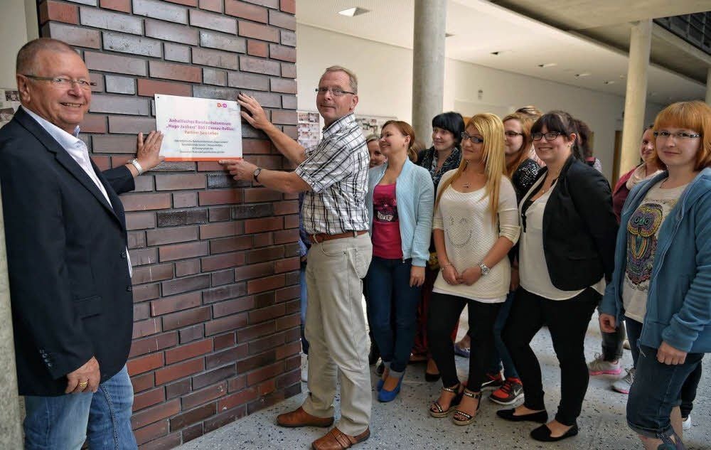 DSD-Geschäftsführer Heinz Robens (l.) und Schulleiter Hans-Georg Baumbach zeigen das neue Schild mit dem Titel „DSD-Partnerschule“. Es soll einen würdigen Platz im Foyer des Berufsschulzentrums finden.