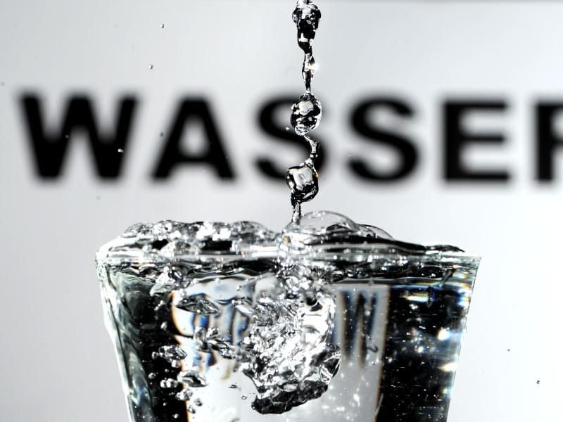 Trinkwasser wird vor einem „Wasser” -Schriftzug in ein Glas gegossen. Foto: Daniel Reinhardt/Archiv