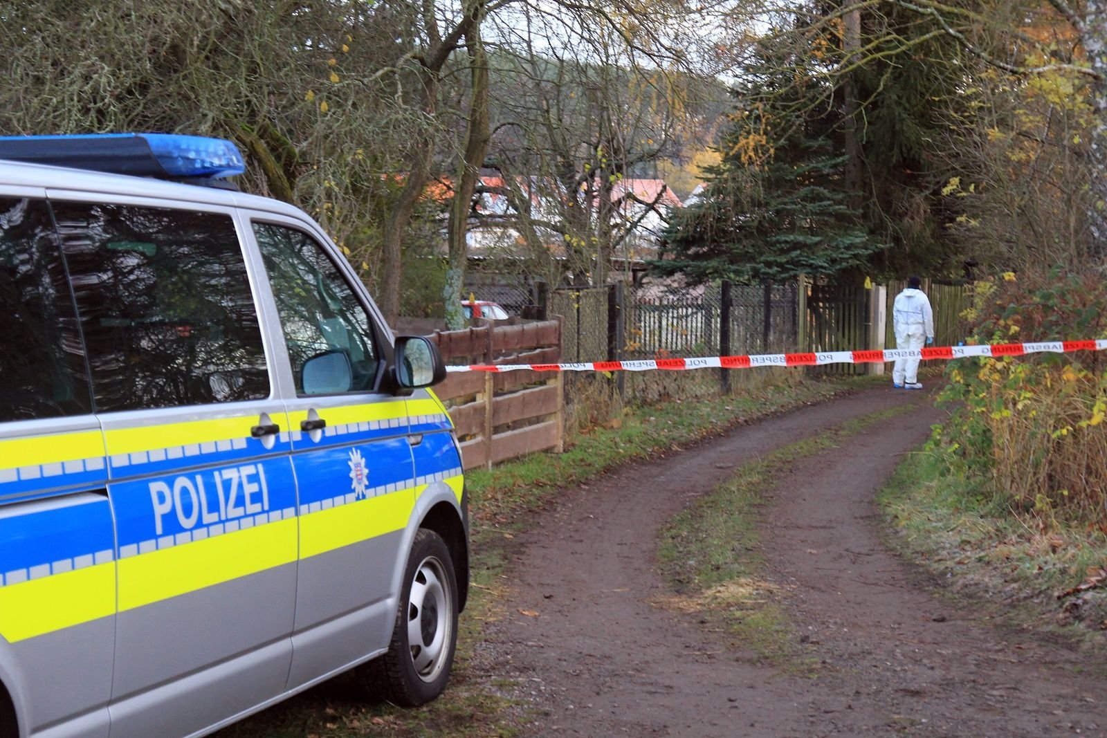 Polizei und Spezialisten des Landeskriminalamtes untersuchen einen Tatort in Geraberg, wo eine Frau tot in ihrem Garten aufgefunden worden war.