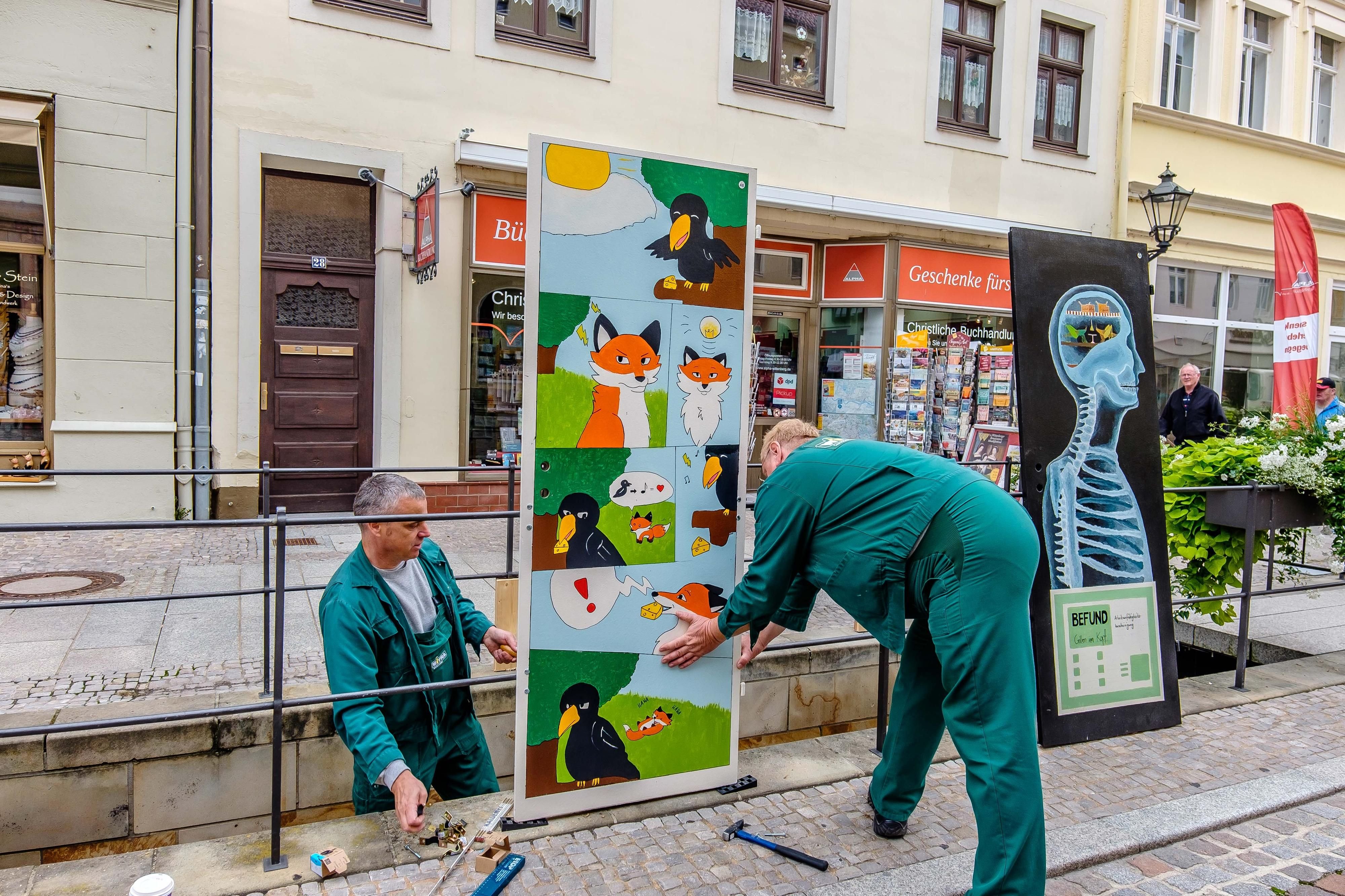 Mitarbeiter der WITRA installieren die 95 Türen zur Reformation entlang des Baches in Wittenberg.