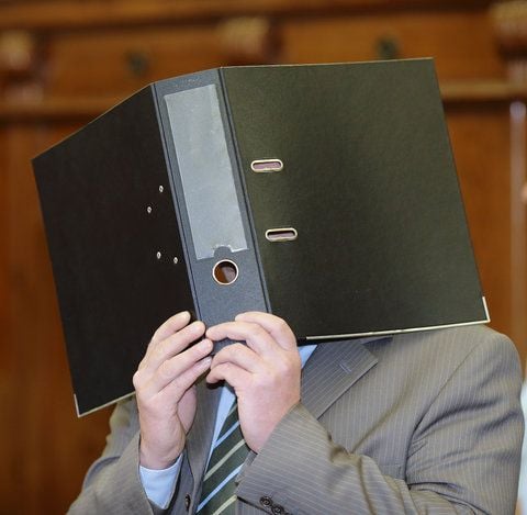 Der Angeklagte Titus S. hält sich beim Prozess um das Zugunglück von Hordorf im Landgericht in Magdeburg einen Ordner vor sein Gesicht. Er wurde nun zu einer Bewährungsstrafe von einem Jahr verurteilt. (FOTO: DPA)