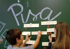 Zwei Schüler aus der Haidhausener Flurschule in München arbeiten mit Worten vor dem Wort Pisa an der Tafel. (Foto: dpa)