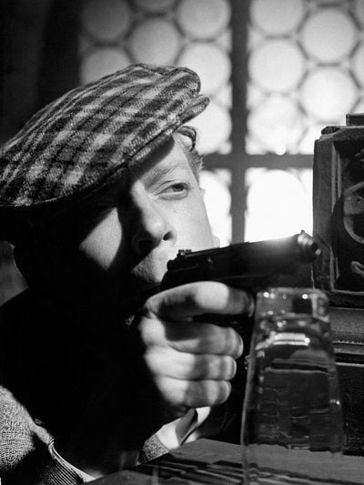 Kriminalist Holms (Rolf Herricht) zielt im Kinofilm «Hände hoch oder ich schieße» mit einer Pistole. 1966 wurde der Film von der SED als politisch bedenklich eingestuft und verboten. (FOTO: DPA)