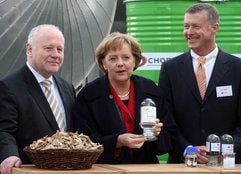 Bundeskanzlerin Merkel steht mit der Probe eines neuen Biotreibstoffes «Sundiesel» neben dem Geschäftsführer der Choren Industries GmbH Freiberg, Tom Blades (r.) und Sachsens Ministerpräsident Georg Milbradt. (Foto: dpa)