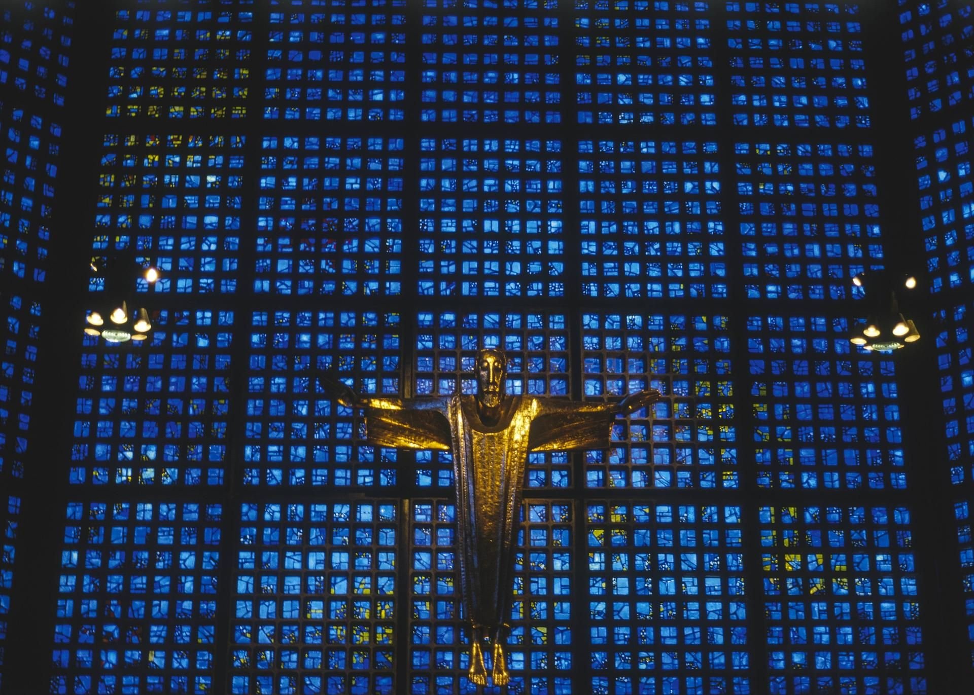 Die Christusfigur vor blauen Mosaikfenstern in der Gedächtniskirche in Berlin.