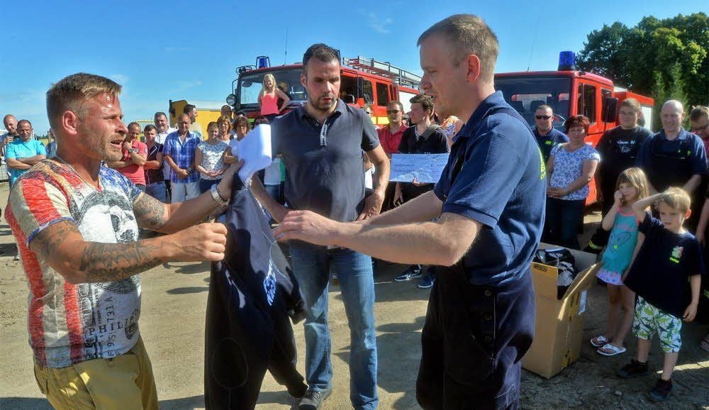 Steve Funk (r.) nimmt die Sweat-Shirts für die Nachterstedter Wehr entgegen.