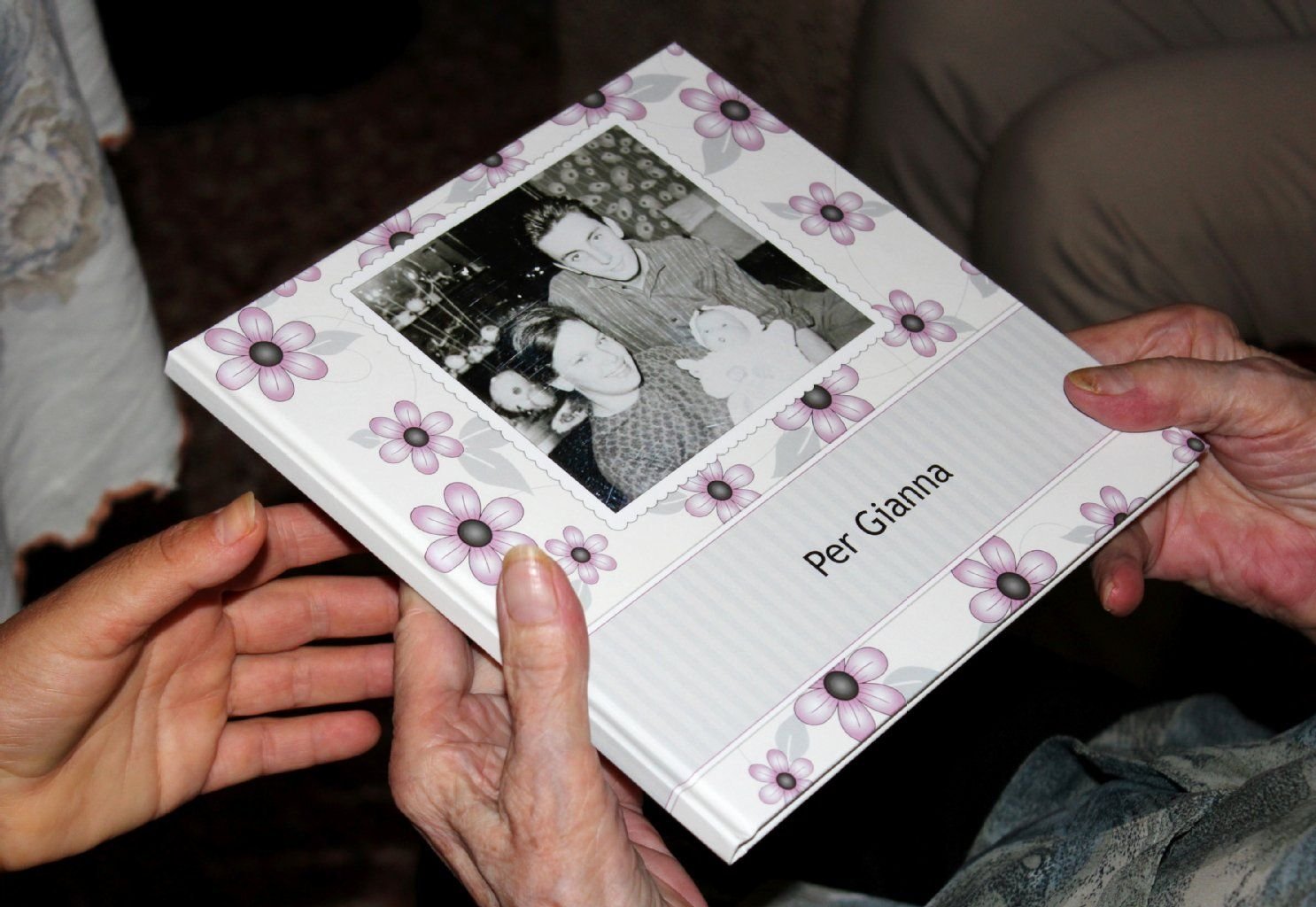 Die 91 Jahre alte Italienerin Gianna hält einen Bildband mit Fotos der Familie ihrer Tochter Margot Bachmann in den Händen, auf dem Titel ist Frau Bachmann mit ihrem Ehemann und ihrer erstgeborenen Tochter zu sehen - links die Hand einer italienischen Angehörigen von Gianna.