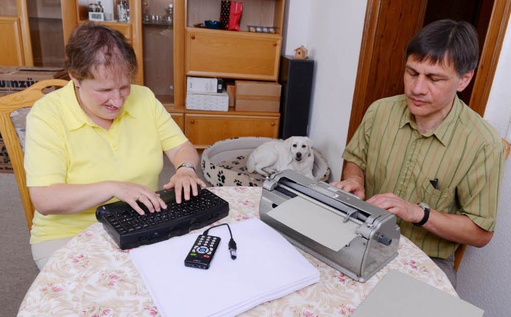 Corinna und Uwe Blum nutzen Punktschriftschreibmaschine und die Tastatur für den Computer mit der Punktschriftzeile zum Schreiben.