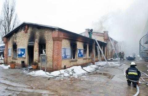 Feuerwehrleute beobachten auf der Bootswerft Marina Lanke in Berlin das qualmende Dach eines Gebäudes. Bei dem am Morgen ausgebrochenen Feuer ist ein Millionenschaden entstanden. (FOTO: DPA)