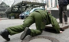 Ein Polizeibeamter schaut am Dienstag (27.04.2004) in Berlin vor dem Hotel Interconti in einen Gulli. In dem Gebäude findet 28. und 29.04.2004 die internationale Antisemitismus-Konferenz der Organisation für Sicherheit und Zusammenarbeit in Europa (OSZE) mit mehr als 600 Delegierten unter starkem Polizeiaufgebot statt. (Foto: dpa)