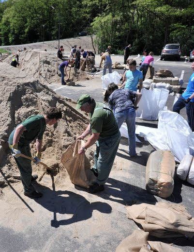 Freiwillige am Bitterfelder Bogen helfen beim Befüllen der Sandsäcke.