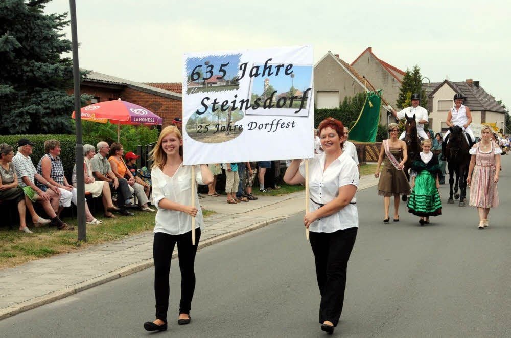 Ute Grundmann und Tochter Jessica weisen zu Beginn des Festzugs auf zwei der Steinsdorfer Feier-Anlässe hin.