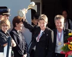 Empfang der frischgebackenen Fußball-Weltmeisterinnen auf dem Frankfurter Flughafen: Bettina Wiegmann (M) winkt mit dem Pokal. Neben ihr steht die Trainer Tina Theune-Meyer (r). (Foto: dpa)