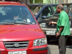 Ein Parkeinweiser in der Kairoer Innenstadt, der in einer kleinen Nebenstraße Autofahrer in die Parklücken lotst, streitet sich mit dem Fahrer des roten Wagens, der sich weigert, ihm etwas zu geben. (Foto: dpa)
