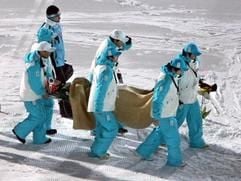 Helfer tragen den verletzten Michael Uhrmann in Sapporo aus der Auslaufzone. (Foto: dpa)