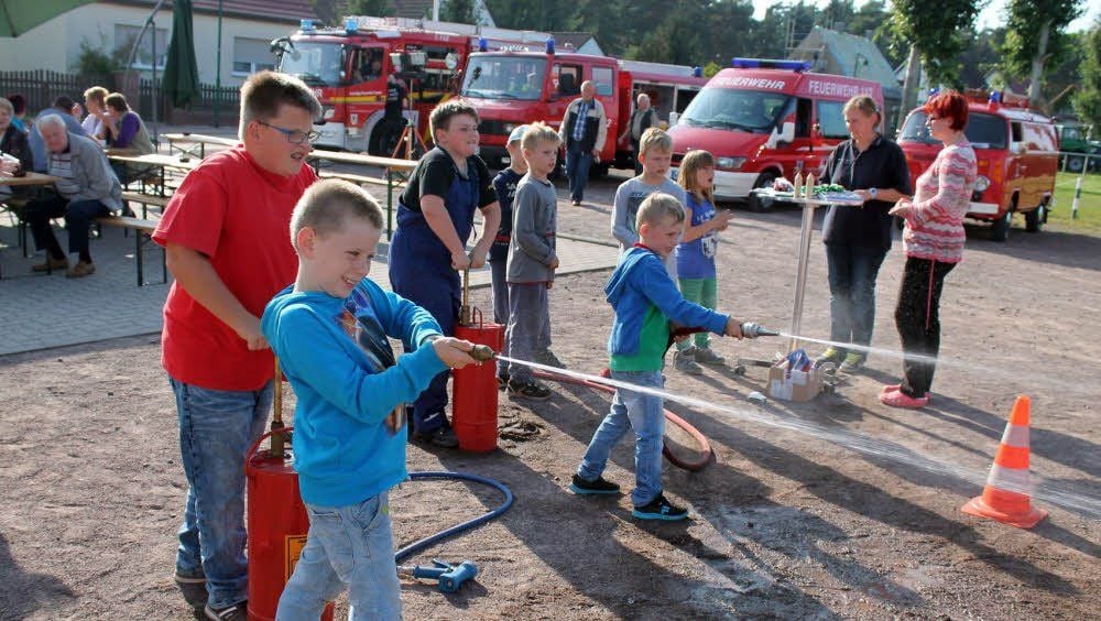 Kinder testen beim Tag der offenen Tür der Feuerwehr in Tornau die Handfeuerspritzen.