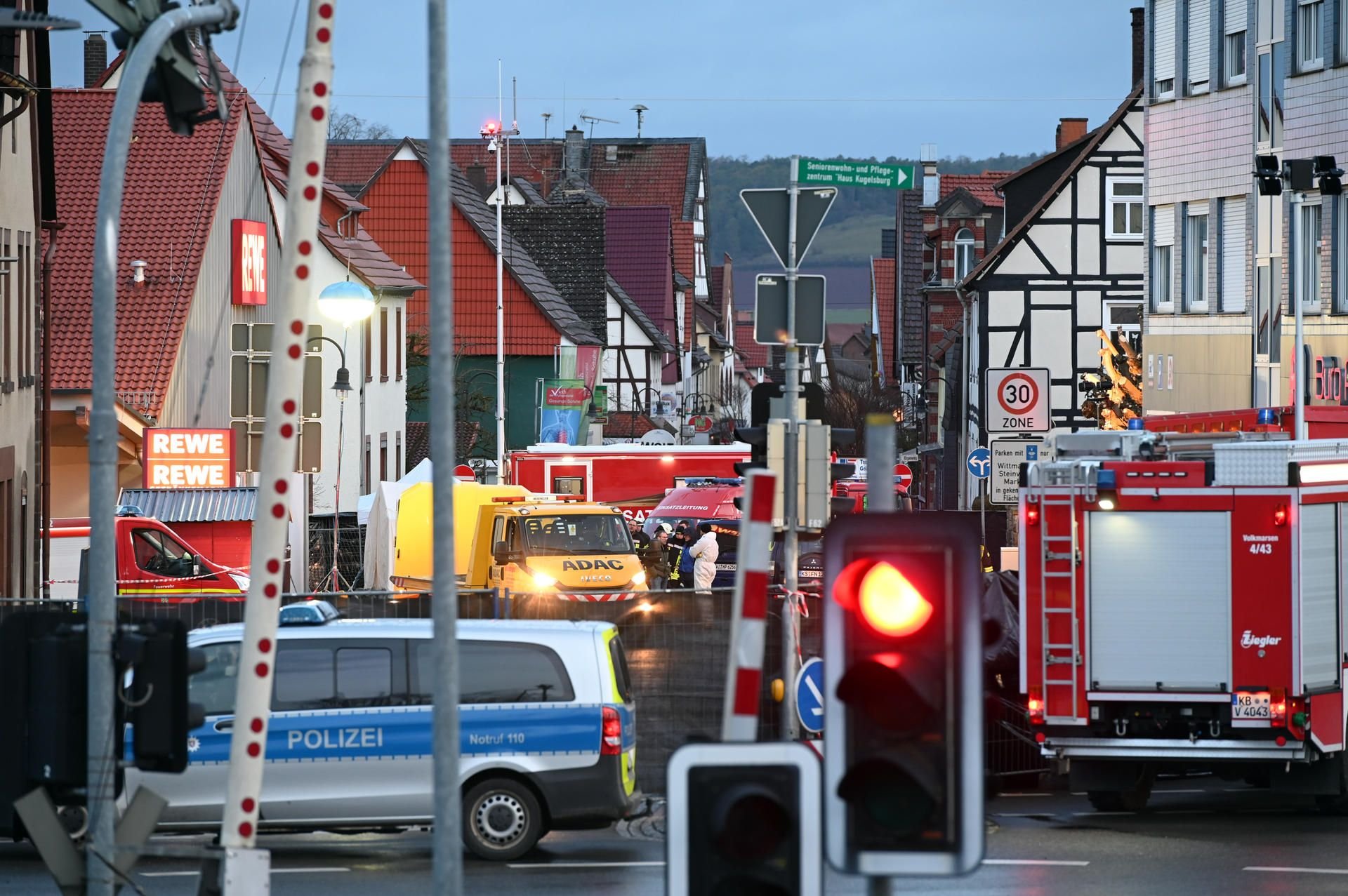 Einsatzkräfte von Polizei und Feuerwehr und ein Abschleppwagen stehen an dem Ort, wo am Vortag ein Mann mit seinem Auto in einen Karnevalsumzug gerast war.